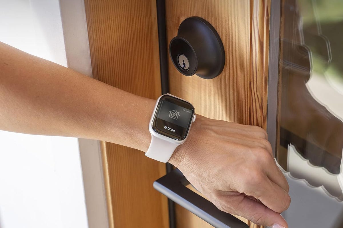 يد تحمل ساعة Apple Watch تقوم بتفعيل قفل Level Plus على باب خشبي.
