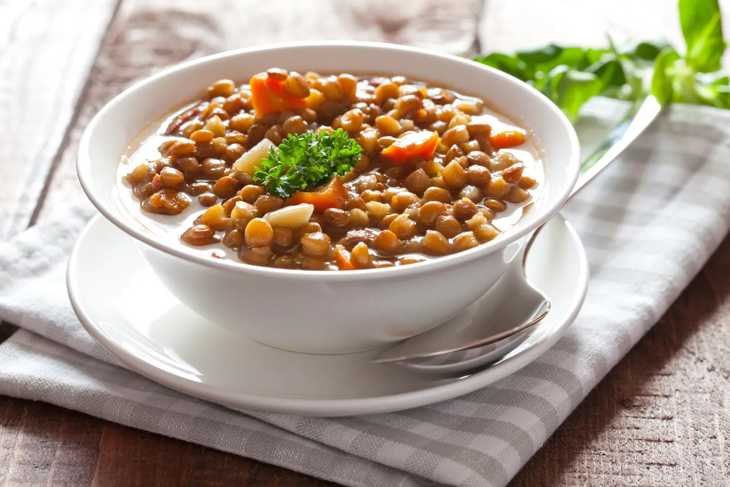 A bowl of lentil soup with garnish resting on a cloth