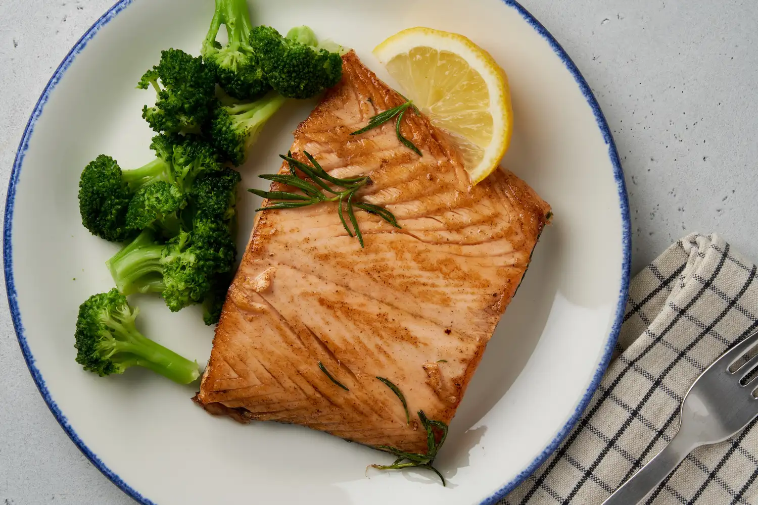 Grilled salmon fillet with broccoli and a lemon slice on a plate